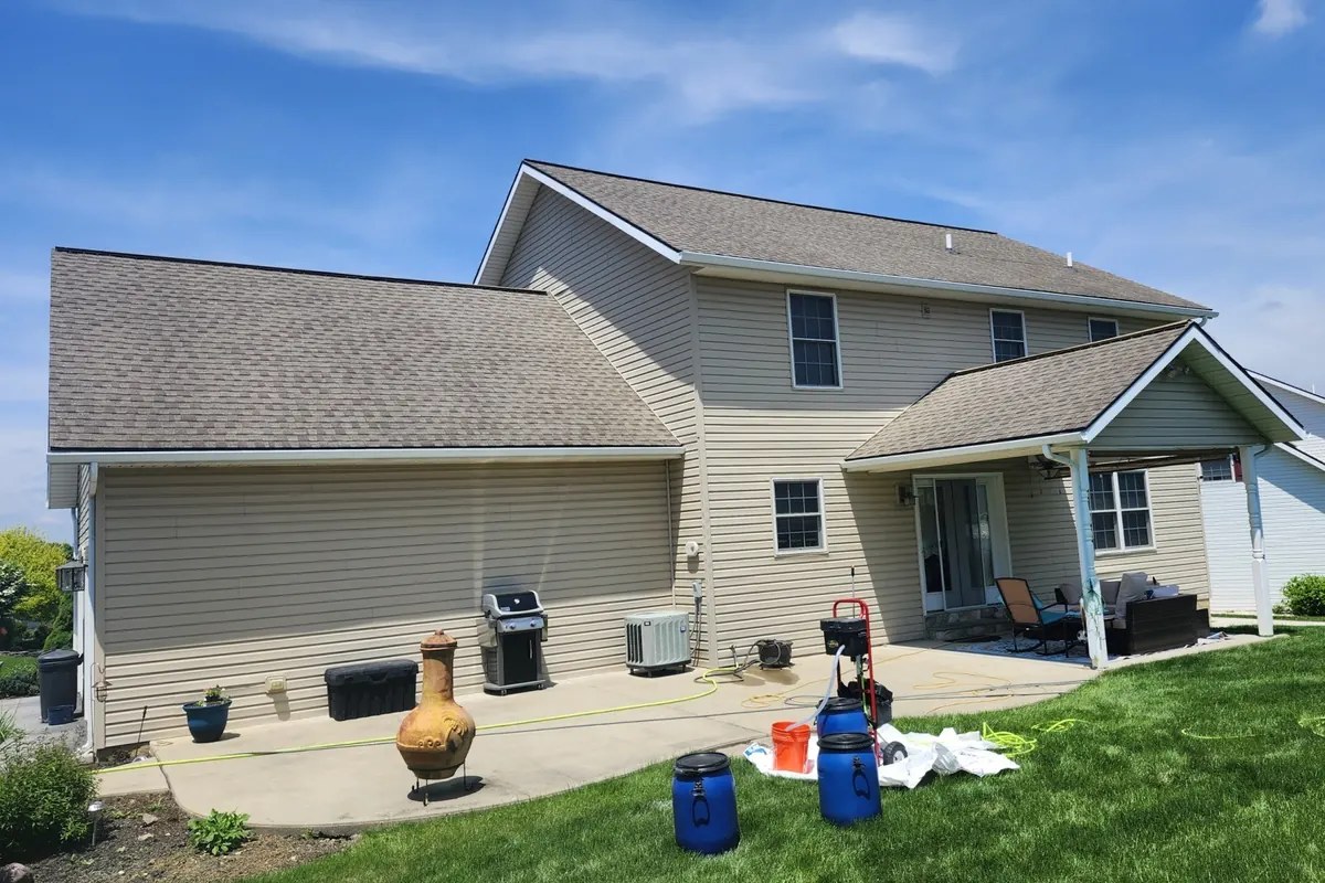 Washed-out light gray-tan asphalt shingle roof on a two-story home before soy roof rejuvenation
