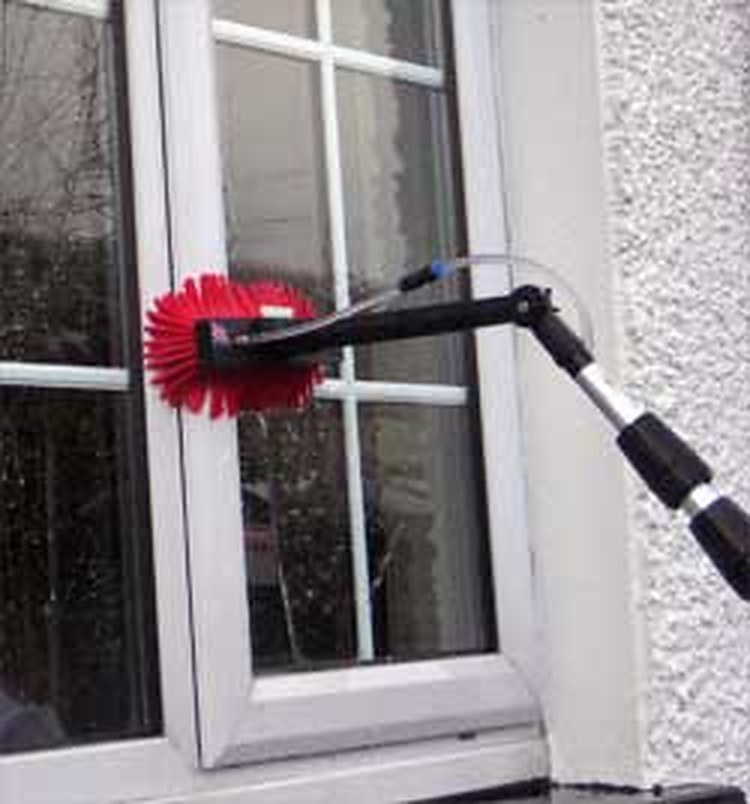 Water-fed pole brush cleaning an exterior window with purified water